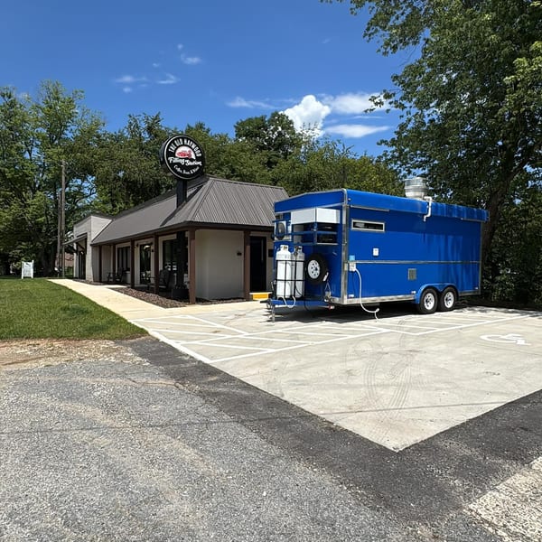 The Old Haywood Filling Station building with a blue food truck parked in front.